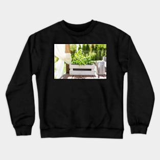 White wooden pot with green herbs on a wooden terrace Crewneck Sweatshirt